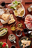 Bruschetta mit Pesto, Minisalami, Parmaschinken, Sardellen, Feta, Oliven, Parmesan, Olivenöl, Riesenkapern und Rotwein