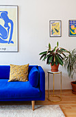 Polstersofa in Königsblau und Beistelltisch mit Zimmerpflanze im Wohnzimmer