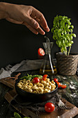 Preparing ravioli with cut cherry tomatoes and fresh basil
