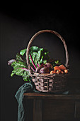 Still life of wicker basket with handle fulled of fresh vegetables from garden