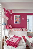 Single bed and rattan furniture in pink-and-white feminine bedroom
