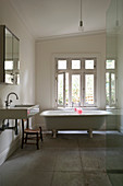 Weißes Badezimmer im schlichten Landhausstil mit freistehender Badewanne und Steinfliesenboden