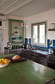 Island counter with moss-green wooden worksurface in vintage-style stainless steel kitchen