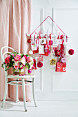 Bouquet of flowers on a chair behind it DIY advent calendar in white, red and pink