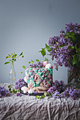 Festtagstorte dekoriert mit Baiser und violetten Fliederblüten