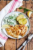 Breaded fish fillet with potatoes and cucumber salad