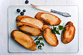 Toasted baguette slices with margarine, mint and blueberries