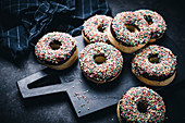 Oven-baked vegan donuts with dark chocolate icing and colourful sprinkles