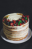 Vanilla sponge cake with cream cheese frosting, berries, gold powder and hazelnut brittle