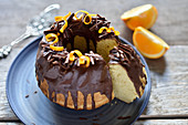 Vegan orange ring cake with chocolate icing, chocolate shavings and orange zest