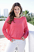 A young woman wearing a fuchsia jumper and white jeans