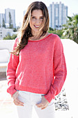 A young woman wearing a fuchsia jumper and white jeans