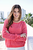 A young woman wearing a fuchsia jumper and white jeans