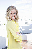 A blonde woman wearing a frilly yellow blouse