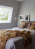 Doppelbett im Schlafzimmer mit grauen Wänden und leichter Dachschräge