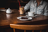 Iced Latte mit Schokokuchen auf Holztisch im Café