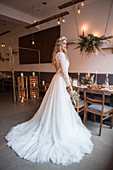 Bride wearing white wedding dress with train in vintage-style restaurant