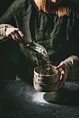Process of making homemade bread dough: Woman hands sifts flour from vintage sieve