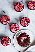 Schokoladen-Cupcakes mit rosa Frosting und getrockneten Rosenblättern