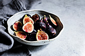 Halved figs in a bowl on a white background
