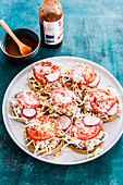 Mexican corn thick tortillas topped with beans purea, meat, onions, cabbage, fresh tomatoes, cheese, radishes and tomatoe sauce
