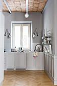 Open-plan kitchen in shades of grey with panelled cabinets and vaulted ceiling