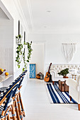 Barstools in open-plan interior with white floor and blue accents