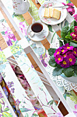 Primulas, tea and cake on DIY palette table decorated with springlike floral pattern