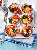 Easter eggs baked in ham with spinach and tomato