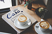 Cappuccinos mit Zeitschrift und Muffin