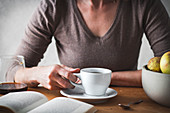 Frauenhand mit Kaffeetasse und Buch