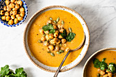 Sweet Potato Soup topped with roasted chickpeas, served in a ceramic bowl.