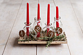 Handmade Advent arrangement of red candles in glass bottles