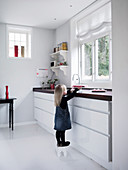 Mädchen auf einem Hocker in moderner Küche mit weißem Boden