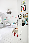 Wooden floor and chandelier in bright child's bedroom decorated entirely in white