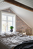 Cosy bedroom with classic wallpaper and sloping ceiling
