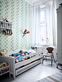 Wooden bed and patterned wallpaper in child's bedroom