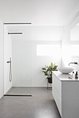 Weißes Badezimmer mit Waschtischmöbel und Duschbereich