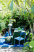 Barbecue and table set in green and blue on summery terrace