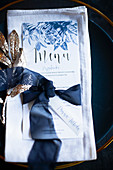 Elegant menu with blue ribbon on napkin