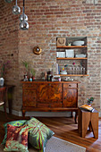 Antique sideboard against brick wall with shelves in niche