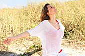 A woman with long hair wearing a red top and white summer jumper