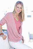 A young blonde woman wearing a pink top and a wrap-around jumper