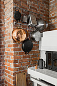 Kitchen utensils hung on brick wall in white kitchen