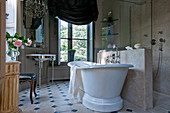 Free-standing bathtub next to half-height partition in French-style bathroom