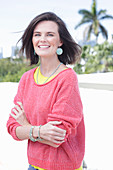 A young woman wearing large earrings, a fuchsia jumper and a yellow top