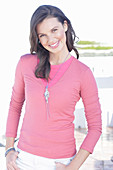A young woman with long hair wearing a pink t-shirt with a long-sleeved shirt on top