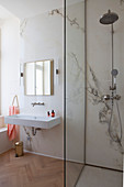 Walk-in shower in elegant bathroom with marble wall and parquet floor