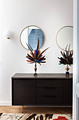 Decorative feather fans on black sideboard in hallway