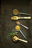 Different types of mustard on spoons, thyme, rosemary